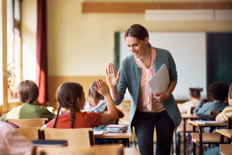 Teacher giving a student a high five in the classroom